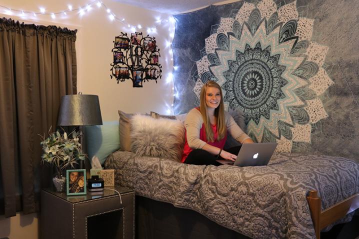 Female student using a laptop on her bed in a room